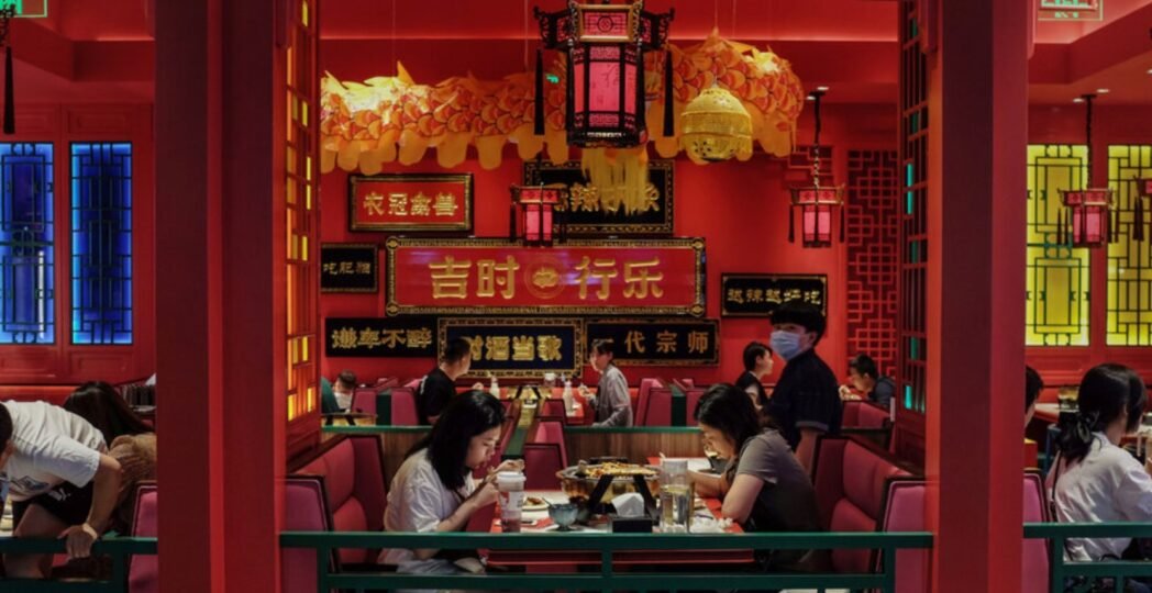 Modern Chinese restaurant interior with red and gold décor, traditional lanterns, and diners enjoying authentic Chinese cuisine.