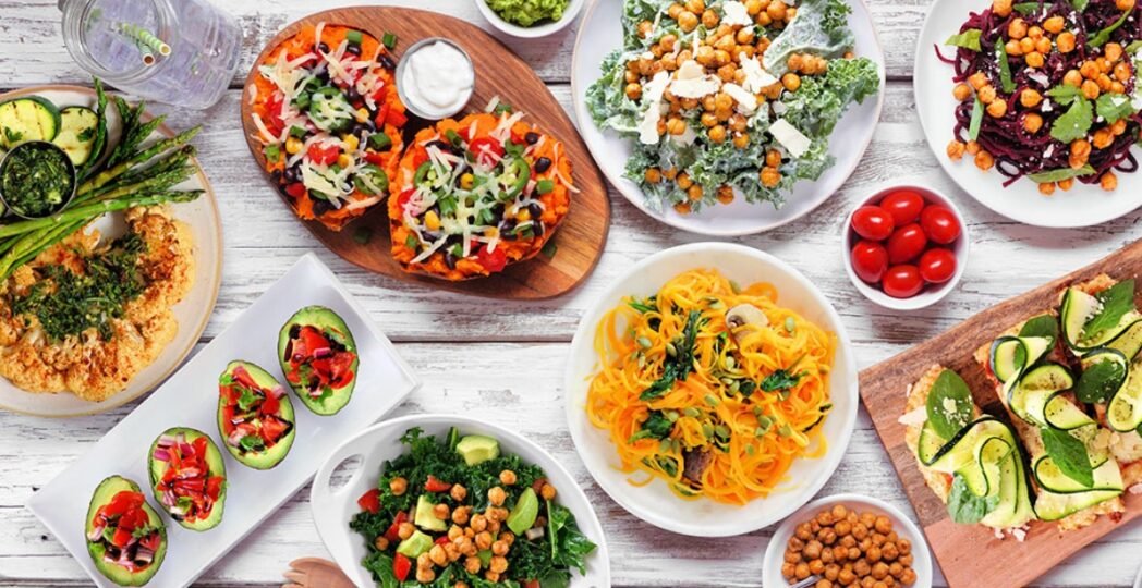 Colorful vegan dishes served on a table, featuring salads, avocado, noodles, and roasted vegetables at vegan restaurants in the USA.