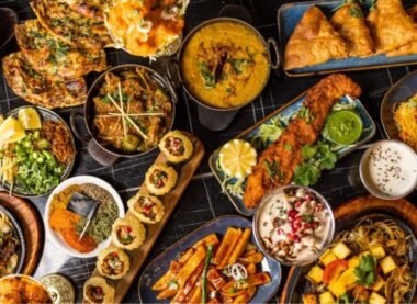 A vibrant spread of traditional Pakistani food including biryani, samosas, curries, naan, kebabs, and chutneys served on a festive table.
