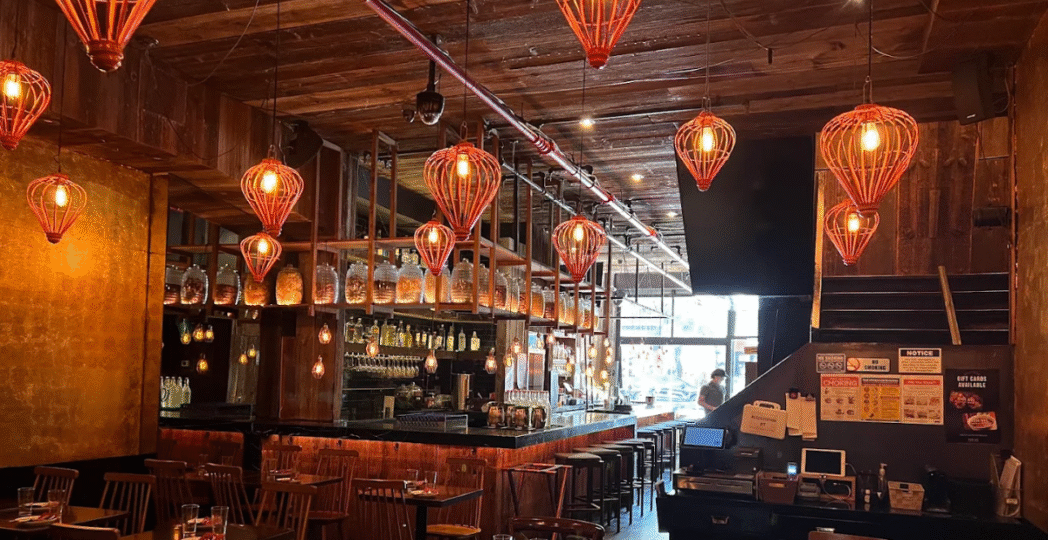 Cozy interior of an Asian restaurant with warm lighting, wooden decor, and hanging lanterns creating a relaxing dining atmosphere.