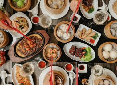 Traditional Chinese food table with dumplings, spring rolls, noodles, and steamed buns.