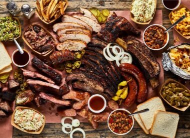 A delicious spread of barbecue ribs, sausages, brisket, mac and cheese, fries, and baked beans showcasing famous foods in the USA.