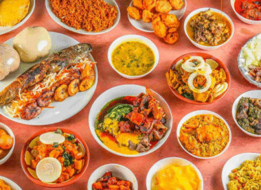 Traditional Nigerian food spread with assorted dishes including jollof rice, grilled fish, fried plantains, soups, and stews.